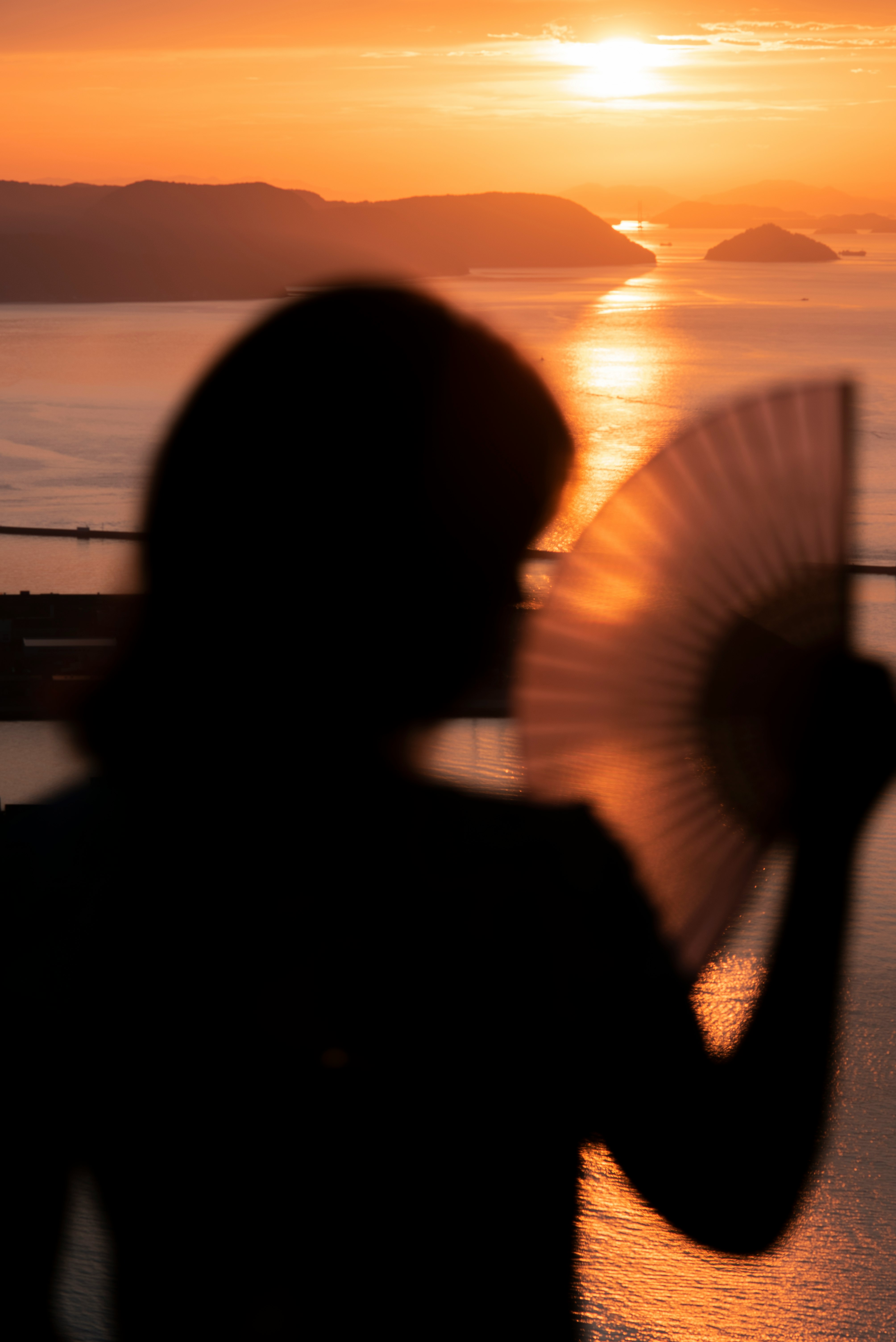 silhouette of woman standing near body of water during sunset